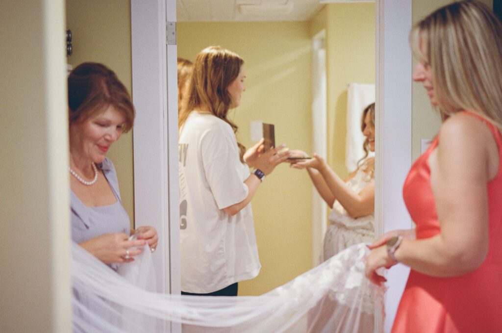 a group of women admire a bride's details while she does her hair