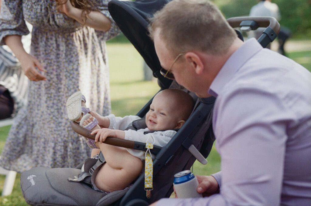 wedding guest sits with baby in a stroller at campground weddnig
