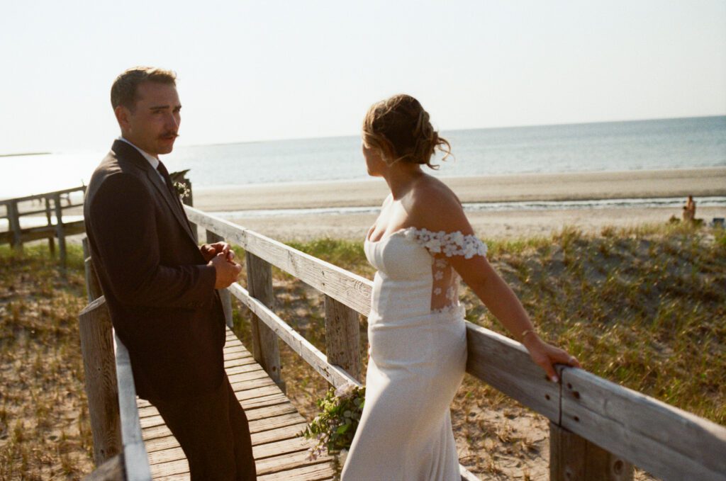 bride and groom look out over Shallow Bay Beach from the boardwalk