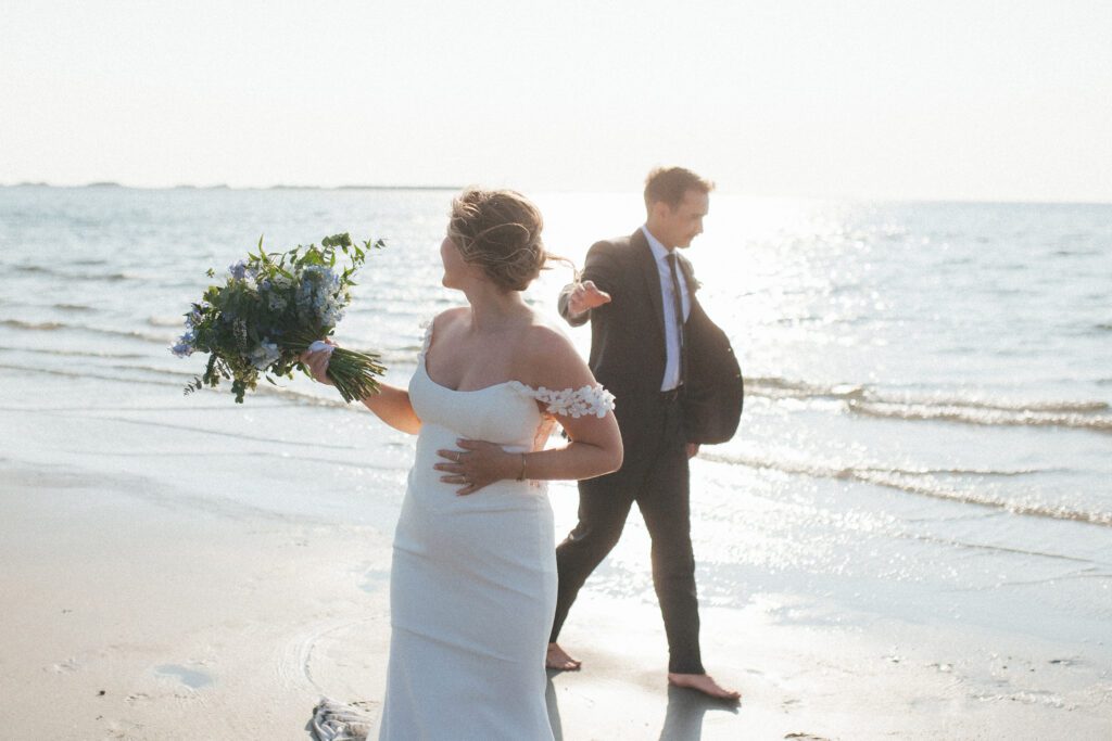 bride and groom explore the beach at sunset