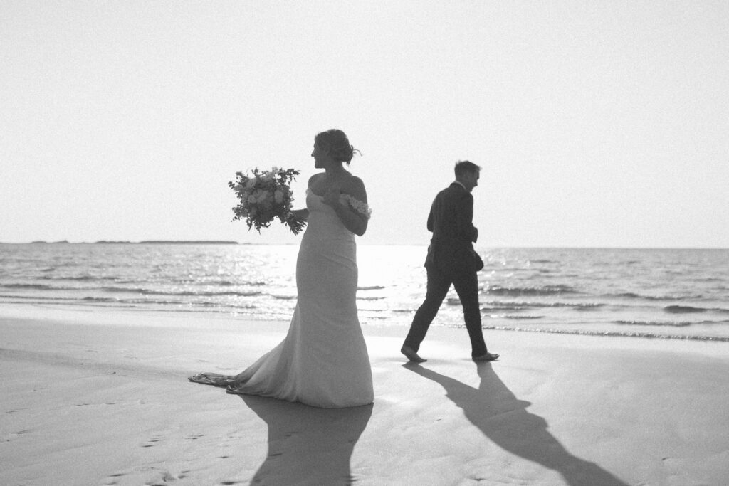 bride and groom explore the beach barefoot at sunset
