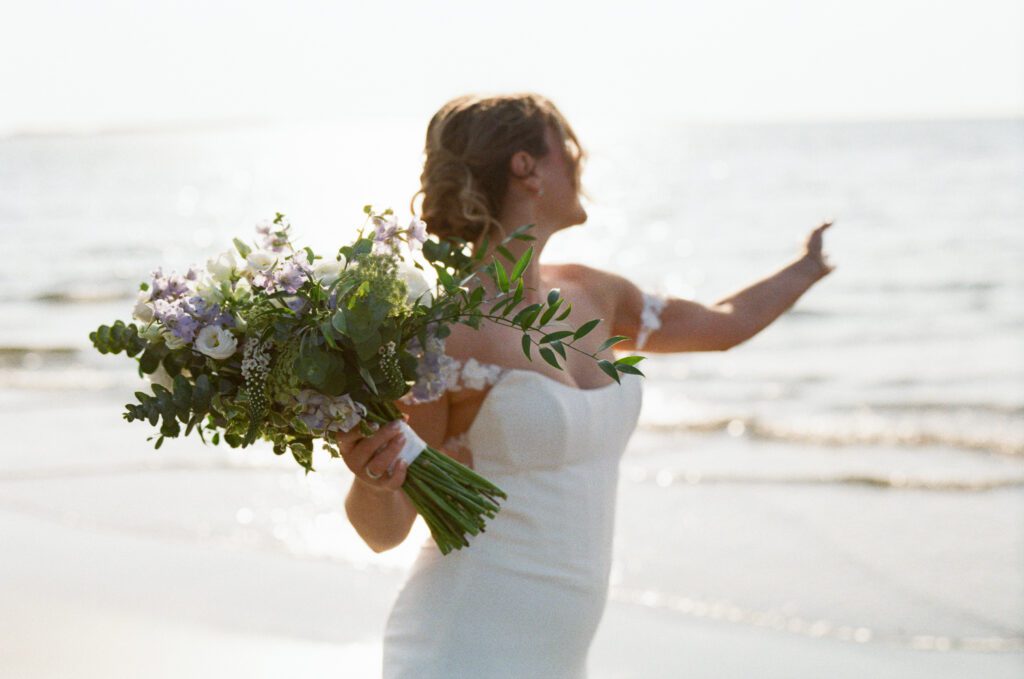 bride twirls around on the beach at sunset