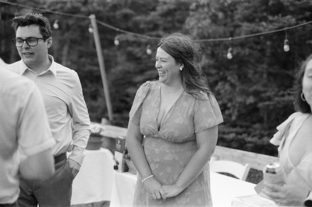 wedding guests laugh outdoors beneath the fairy lights