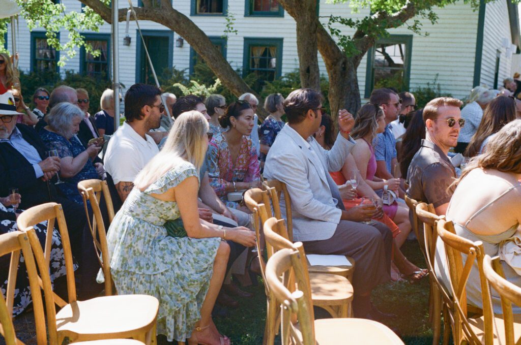 film photo of wedding guests chatting in the sun as they wait for the ceremony to start