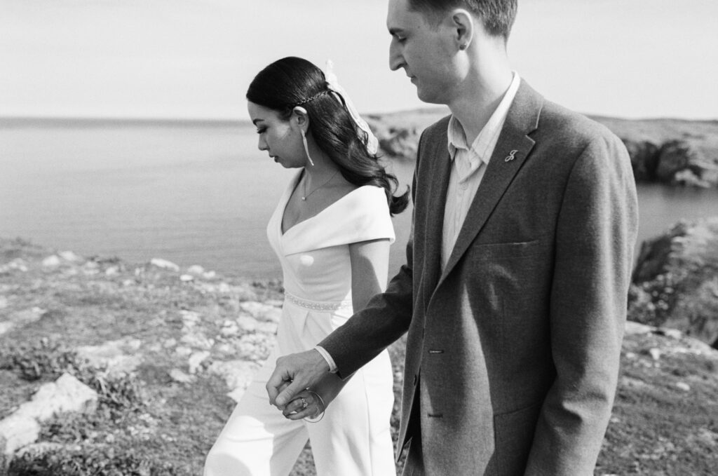 bride and groom walk hand in hand along Newfoundland coast