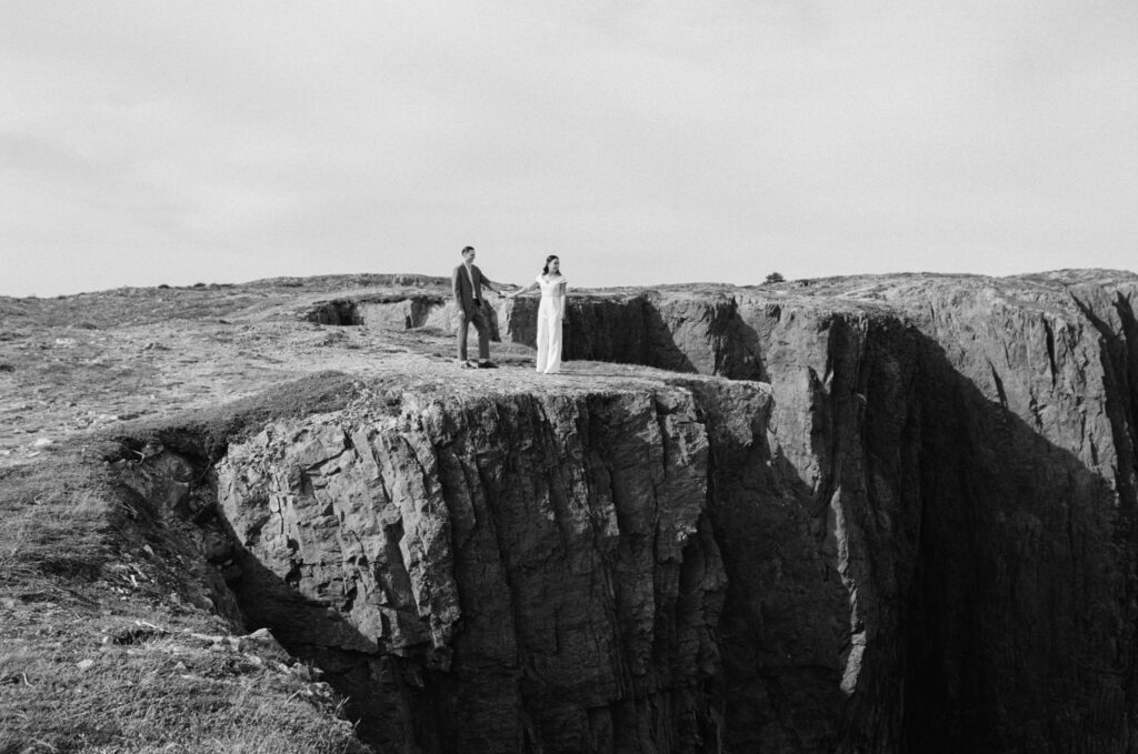bride and groom stand on a rocky cliff