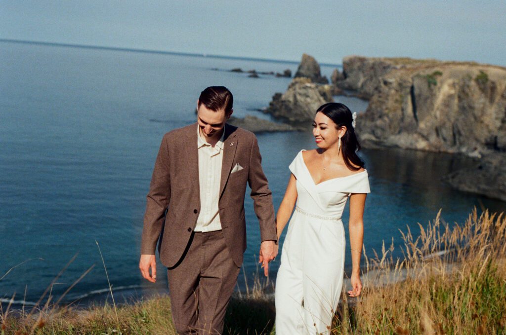 bride and groom laugh beside the ocean with sea stacks in the background