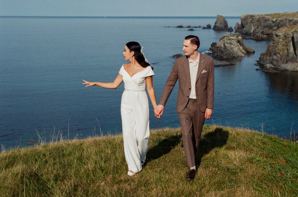 bride points out the view to groom beside the ocean