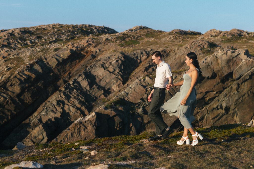 bride and groom walk along rocky cliff