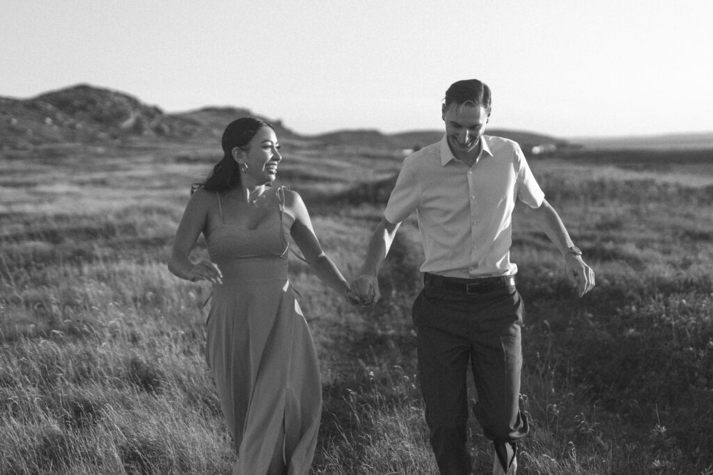barefoot bride and groom run through a meadow of tall grass