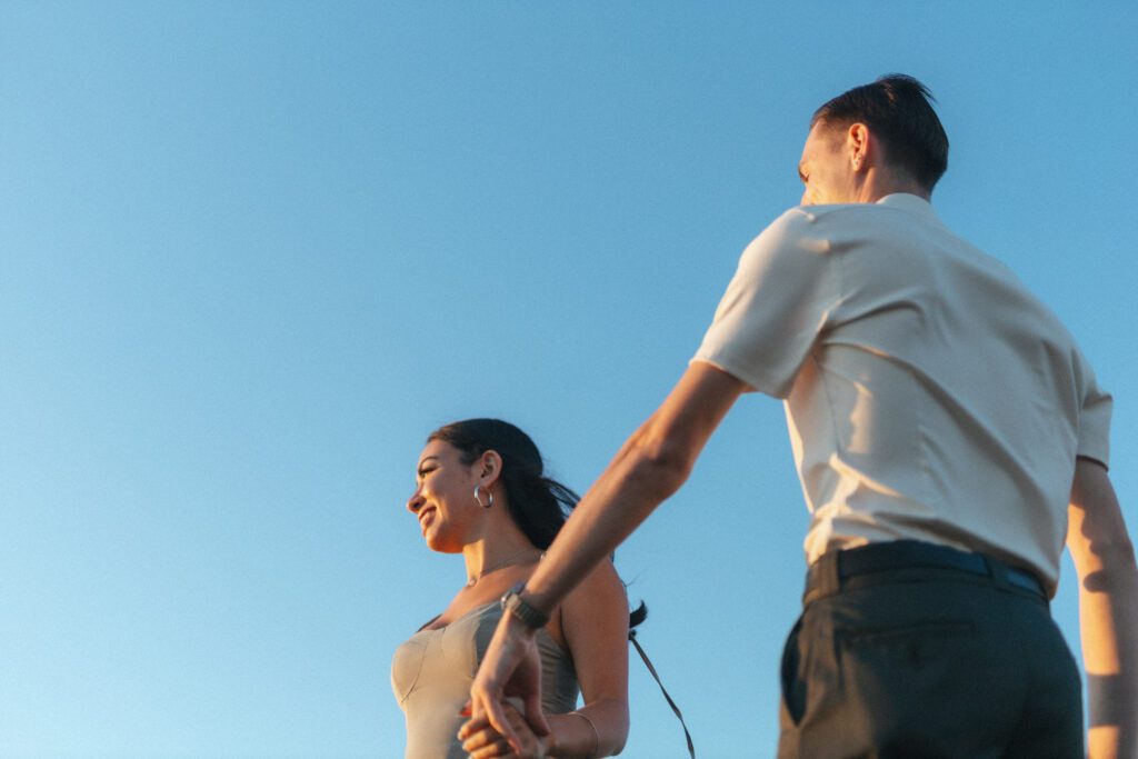 bride and groom spin around against a bright blue sky