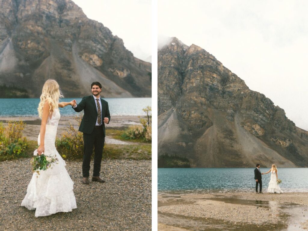 bride and groom walk along the lakeshore holding hands with Crowfoot Mountain rising behind them