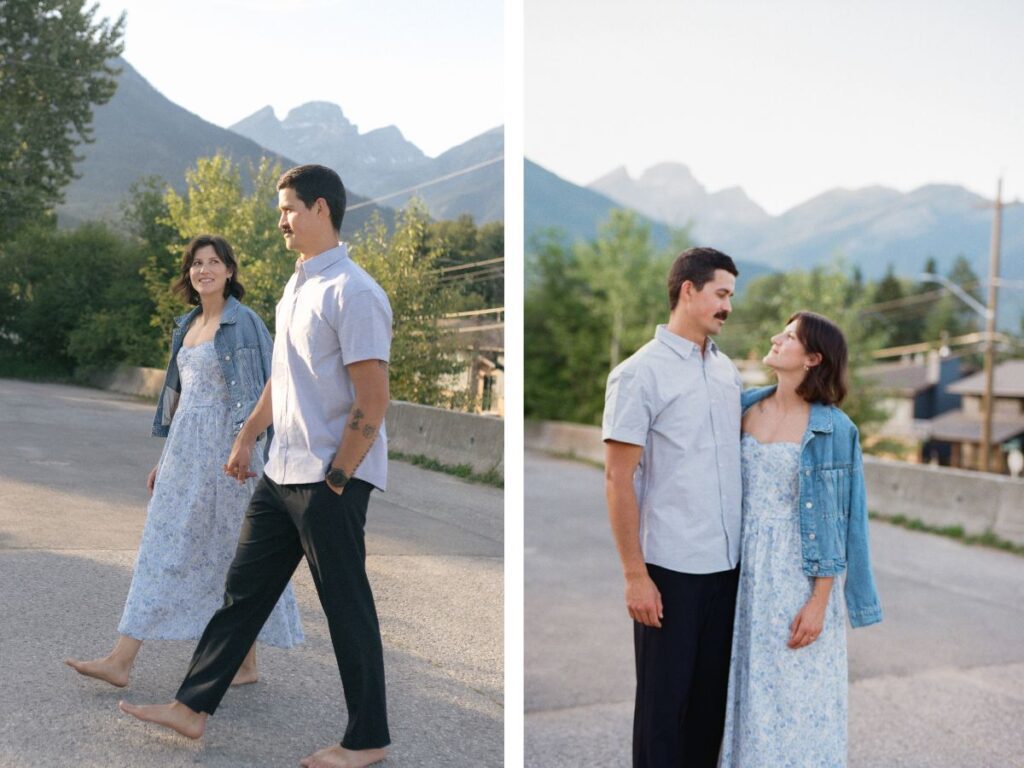 man and woman walk up the street with the three sisters mountain in Fernie rising behind them