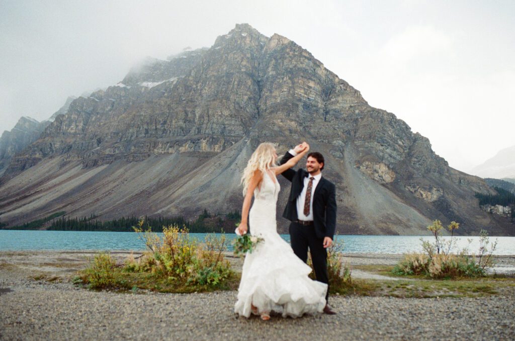groom twirls bride in front of Crowfoot Mountain in Banff National Park