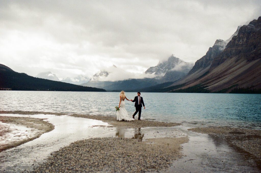 bride and groom spin around on the shore of a mountain lake in Banff