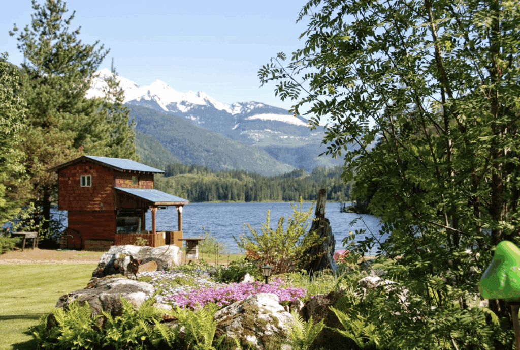 View of Griffin Lake in the Columbia-Shushwap from a large lawn with flower beds over the lake and mountains beyond