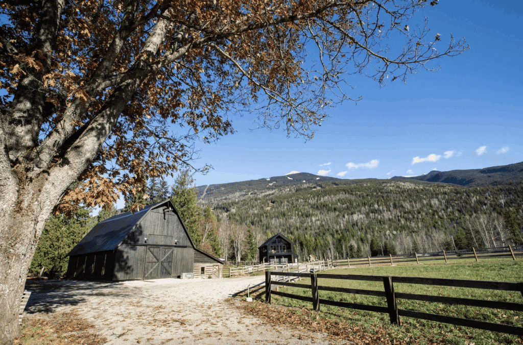 black historic cedar barn at the base of Mount MacKenzie in Revelstoke with a large open field beside it
