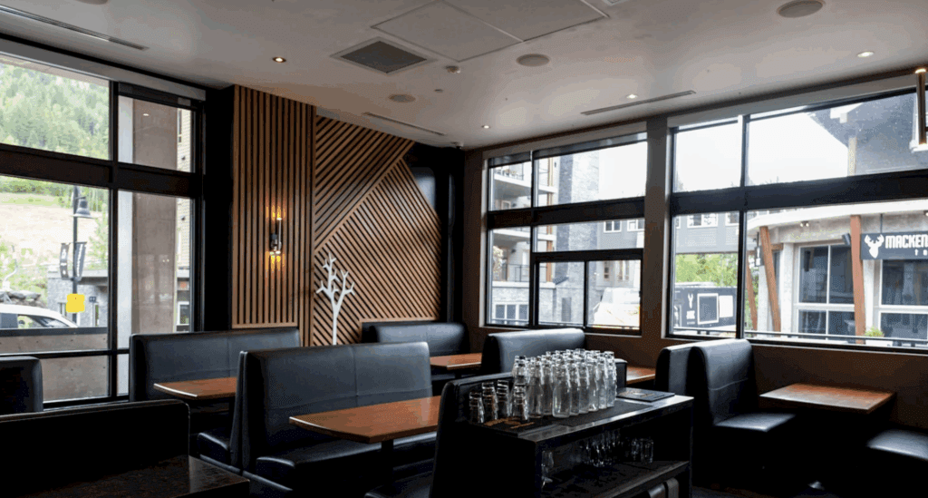 a sleek modern interior of a restaurant in Revelstoke, BC with black leather booths and wood panelled walls