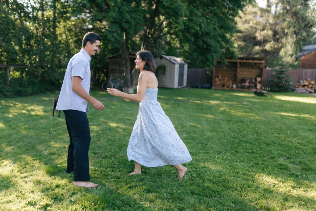 man and woman run through a backyard surrounded by trees