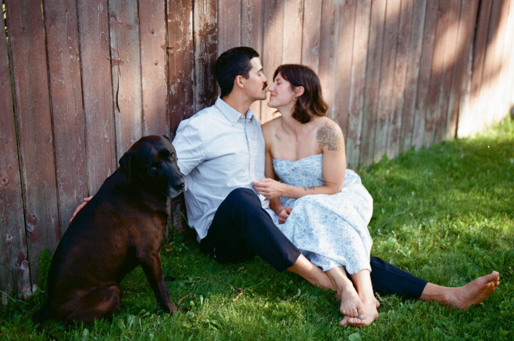 man leaning against a fence kisses his wife's nose