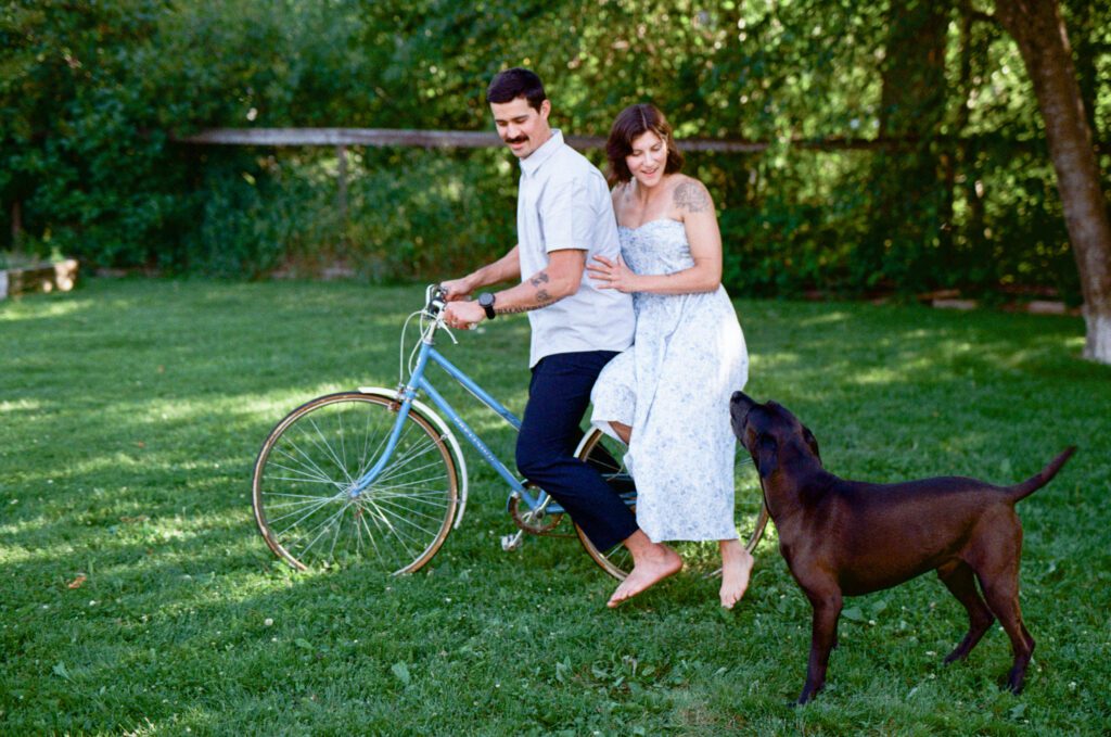man and woman ride a vintage bicycle in the grass