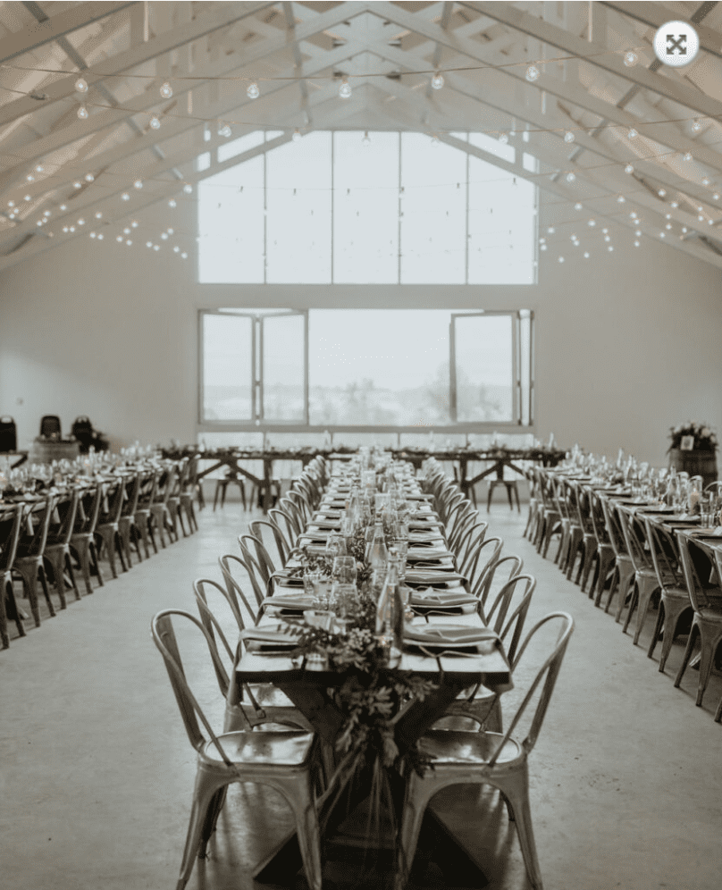 a bright white minimalist interior with long dinner tables set for a wedding on Vancouver Island