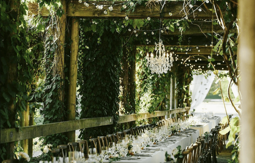 a long wedding table set under a green arbour at UBC Botanical Gardens in Vancouver