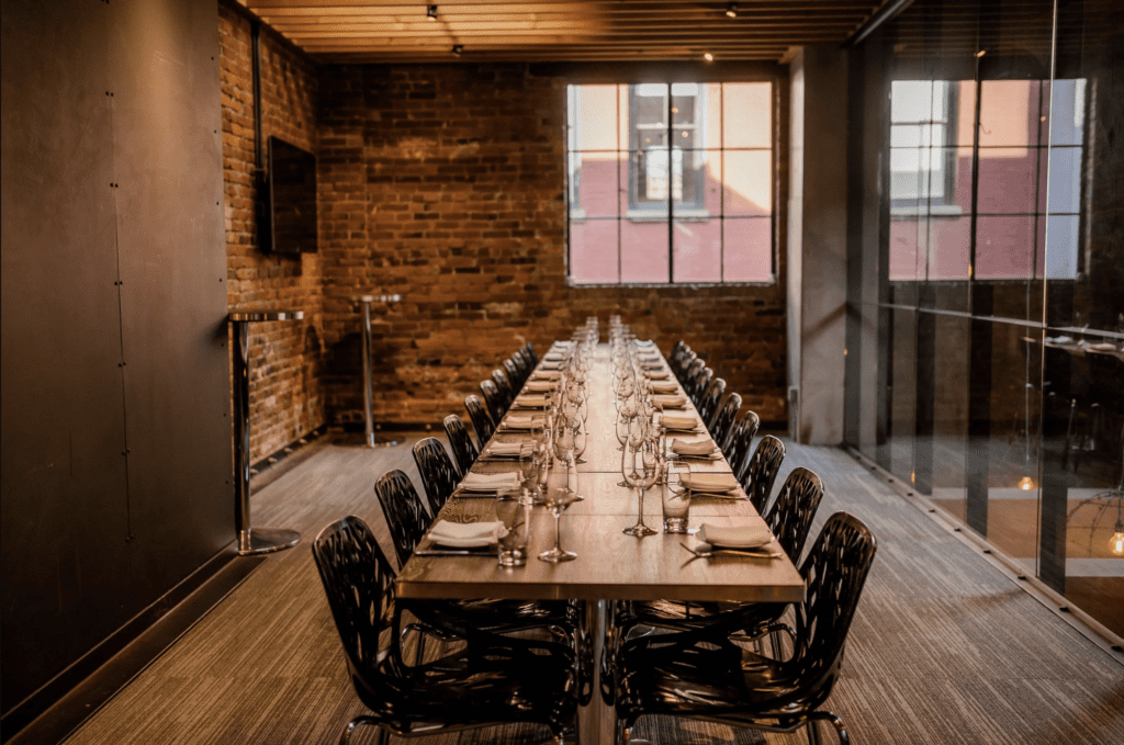 a long dinner table is set for an intimate in a room with heritage brick in Vancouver restaurant L'Abbatoir