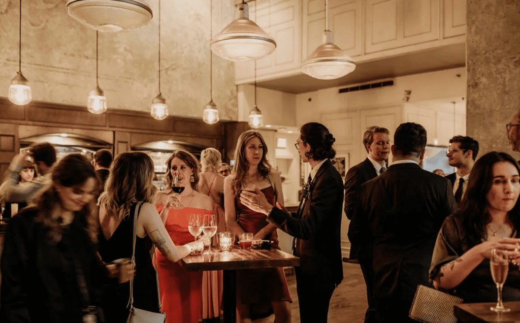 wedding guests mingle in warmly lit, elegant space at Medina Cafe Wedding in Vancouver
